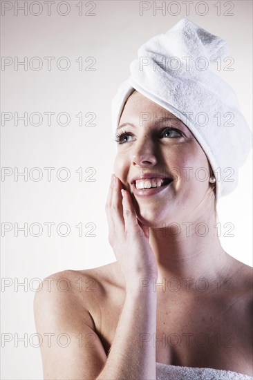 Portrait of a smiling young woman with a towel wrapped around her head