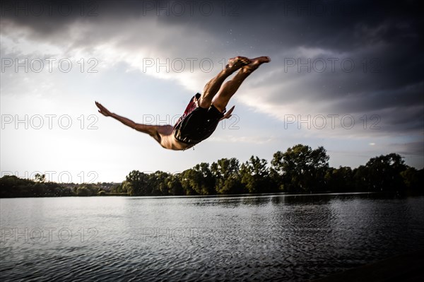 A young man plunging into water from the riverside