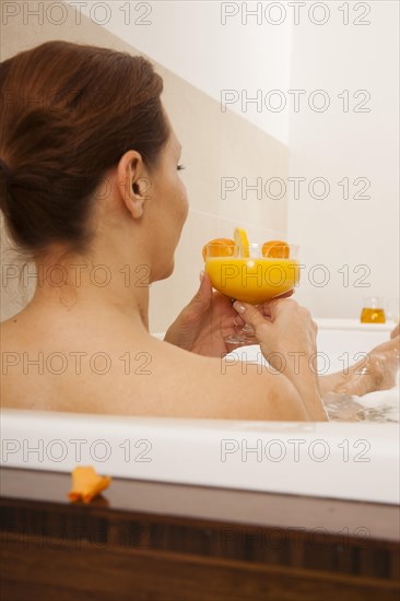 Woman taking a bath and drinking a juice