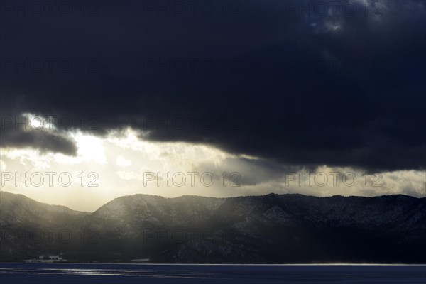 Sun breaks through the clouds at the frozen Lake Kussharo