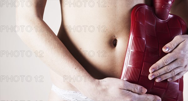 Young woman holding a hot water bottle on her stomach