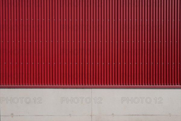 Wall of a factory building with red corrugated iron and concrete