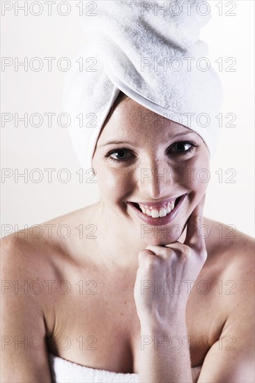 Portrait of a smiling young woman with a towel wrapped around her head