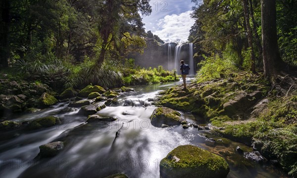 Young man standing in front of waterfall