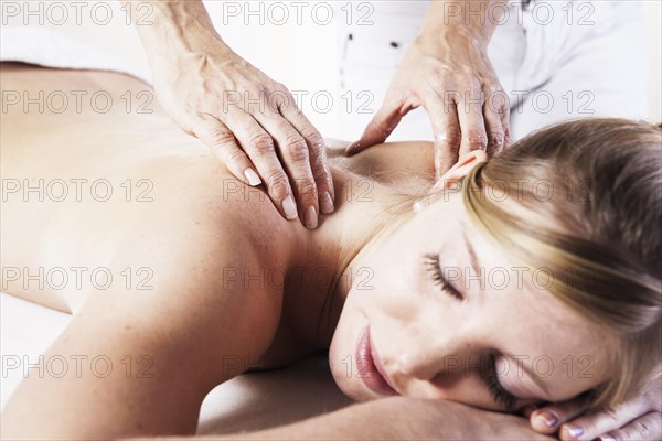 Young woman being massaged on the back by a therapist