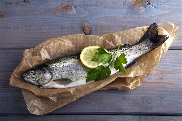 Fresh brook trout in baking paper on a wooden surface