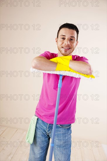 Smiling man leaning on a mop