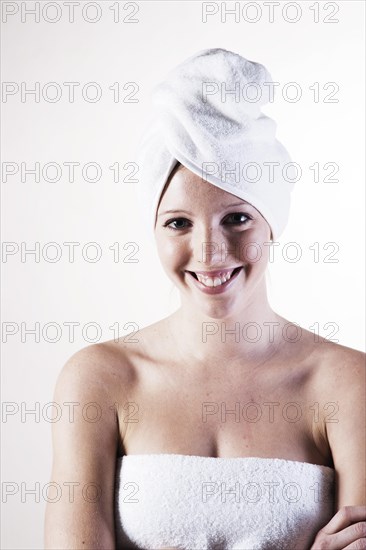 Portrait of a smiling young woman with a towel wrapped around her head