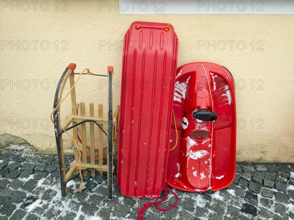 Various sledges leaning against a house wall