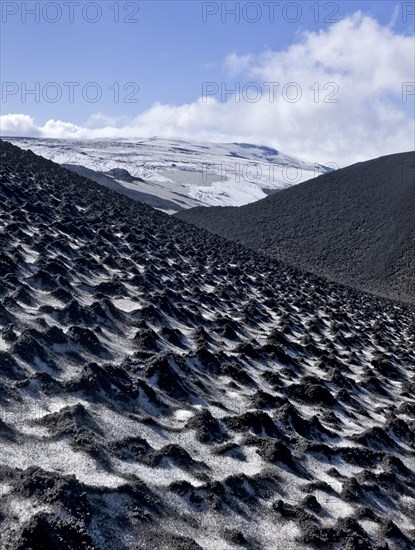 Ash-covered snowfield with the Eyjafjallajokull on the long-distance hiking trail from Skogar via Fimmvorouhals to the Thorsmork mountain ridge