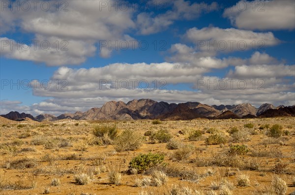 A blue sky with white clouds over the mountainous desert landscape