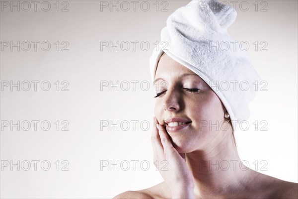 Portrait of a smiling young woman dreaming with a towel wrapped around her head