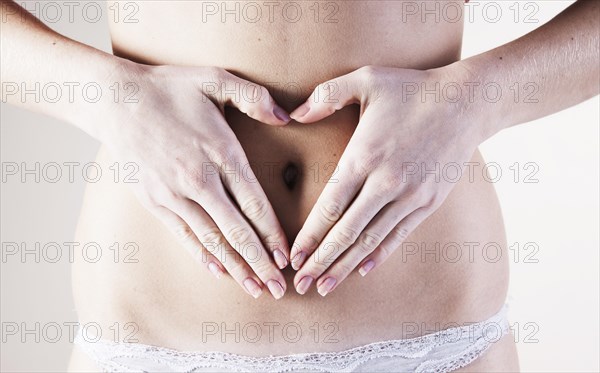 Young woman with her hands forming a heart on her belly