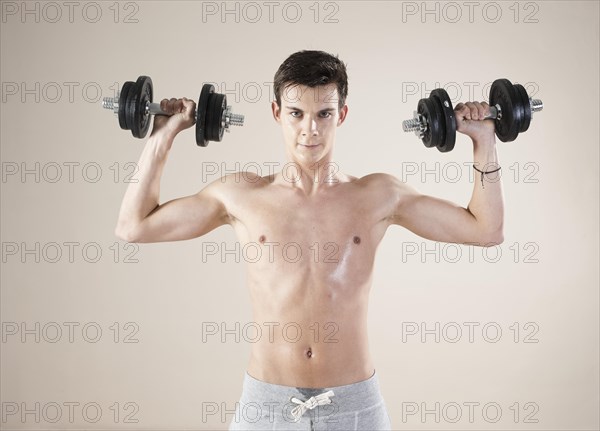 Young man doing weight training with dumbbells