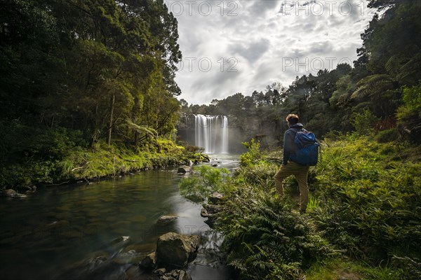 Young man standing in front of waterfall