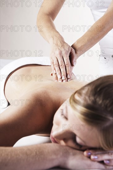 Young woman being massaged on the back by a therapist