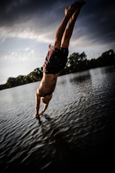 A young man plunging into water from the riverside