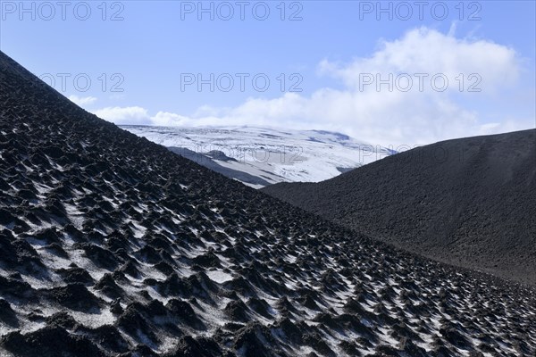 Ash-covered snowfield with the Eyjafjallajokull on the long-distance hiking trail from Skogar via Fimmvorouhals to the Thorsmork mountain ridge