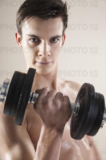 Young man doing weight training with dumbbells