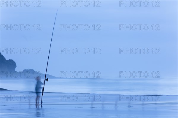 Child on beach with a fishing rod at dusk