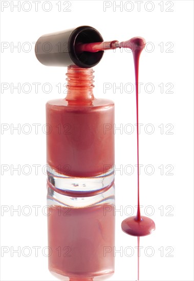 Nail varnish dripping from a nail varnish brush balanced on a nail varnish bottle