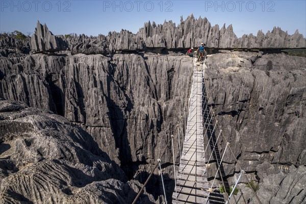 Tourist on suspension bridge over gorge in rugged limestone rocks