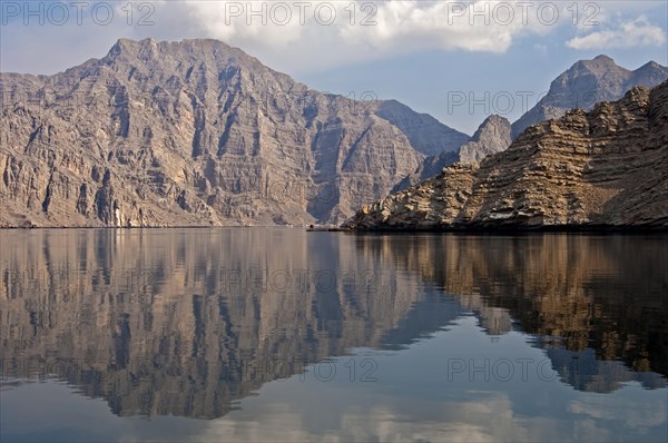 Reflection of a barren mountain range in the Khor Ash Sham Fjord