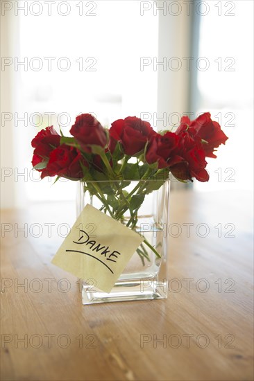 Red roses in vase with the note 'danke'