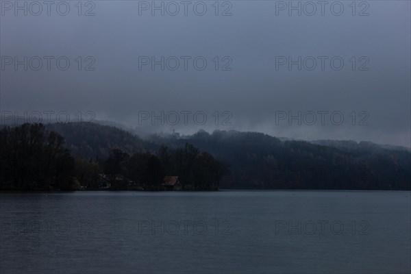 Autumn fog over the lake with a small church