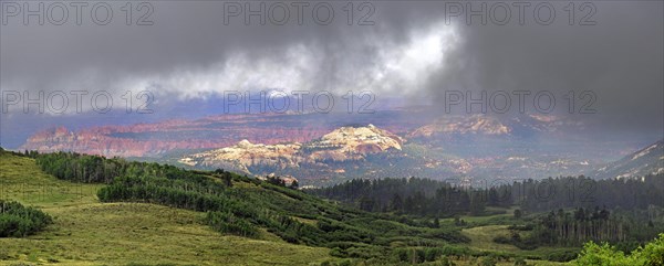 View through the clouds from the green forested Boulder Mountain towards Capitol Reef