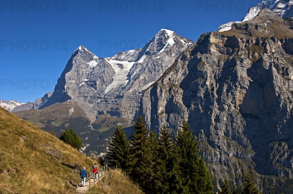 Hikers at the foot of Eiger and Moench Mountains and Eiger glacier