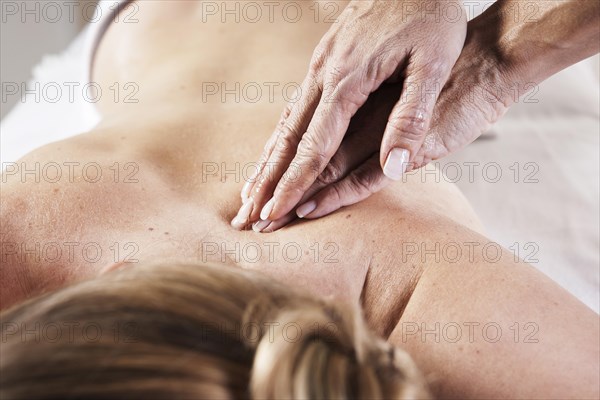 Young woman being massaged on the back by a therapist