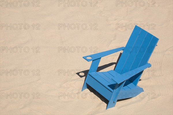 Blue adirondack chair standing on a beach