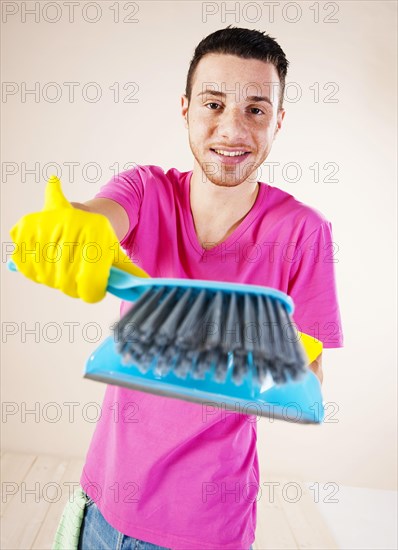 Man holding a hand brush and a dustpan