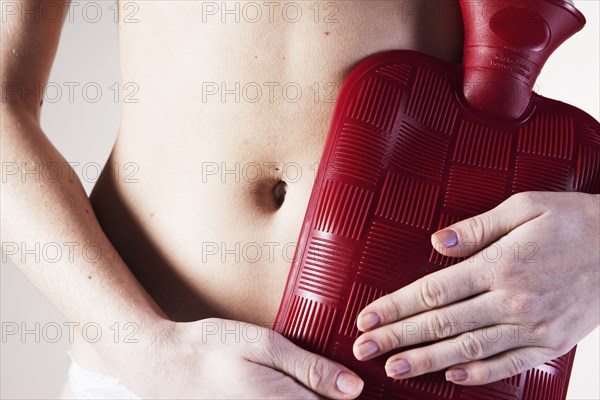 Young woman holding a hot water bottle on her stomach