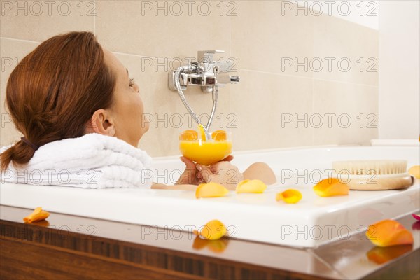 Woman taking a bath and drinking a juice