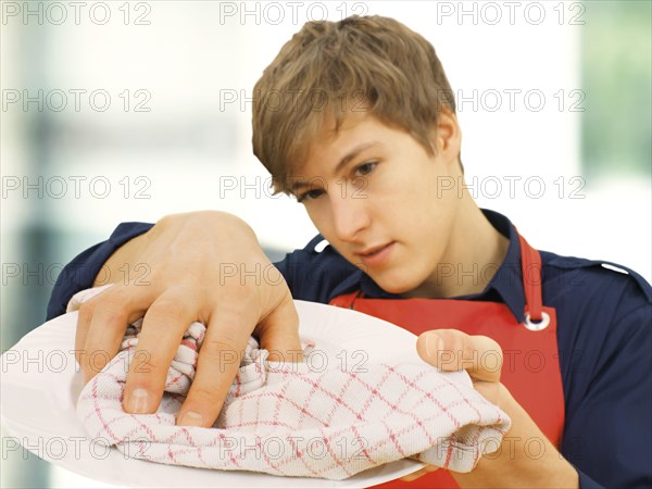 Young man wearing an apron while doing the housework