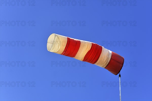 Red and white windsock against a blue sky