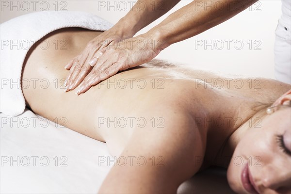 Young woman being massaged on the back by a therapist