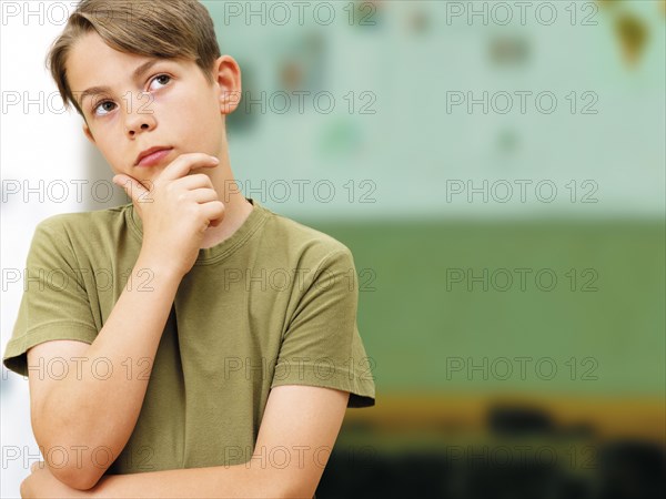 Schoolboy looking thoughtful in a classroom