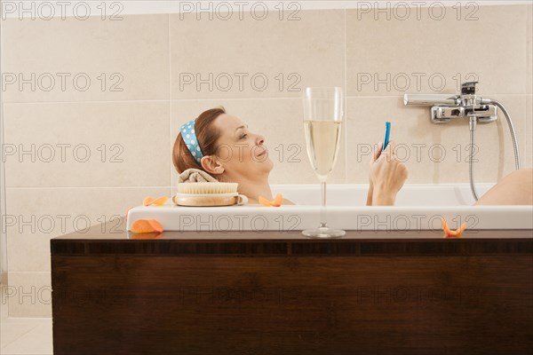 Woman using a mobile phone in the bathtub