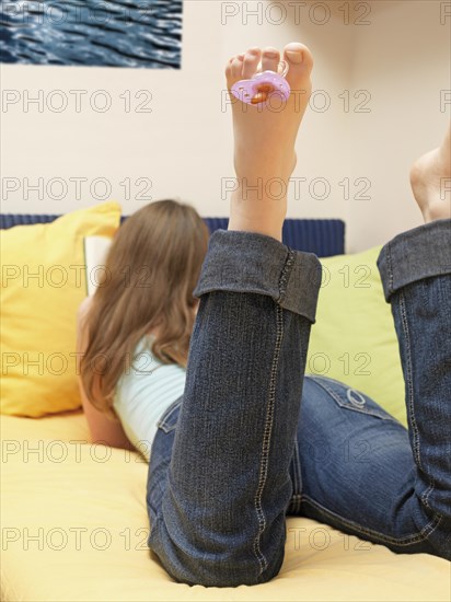 Woman reading with a pacifier hanging from her toe