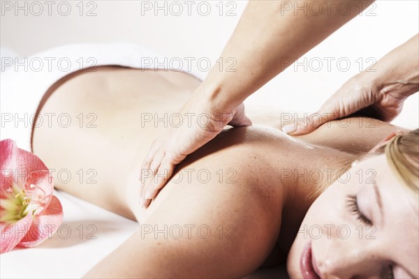 Young woman being massaged on the back by a therapist