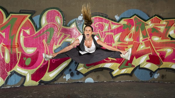 Hip-hop dancer jumping in front of a wall with graffiti