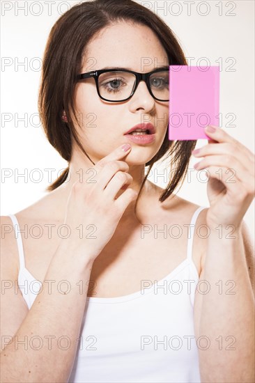 Young woman looking at herself in a cosmetic mirror