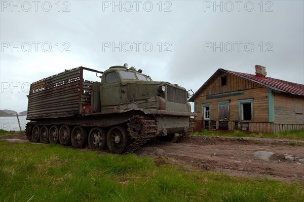 AT-T caterpillar all-terrain vehicle in front of a derelict house in a rural locality