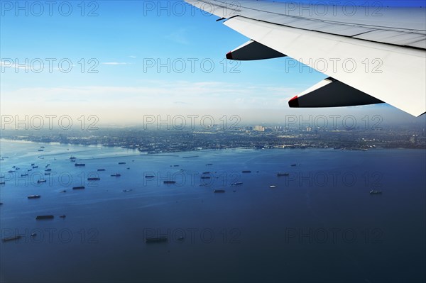 Wing of a plane and views of the port area of Jakarta on landing approach
