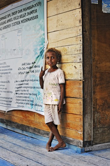 Local child standing against a wooden wall