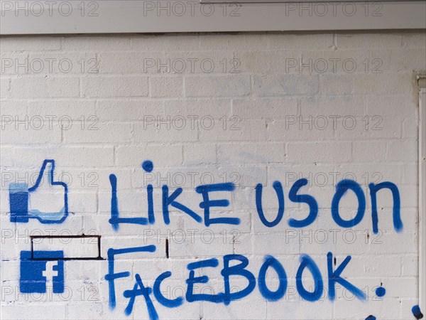 Like us on facebook' call to action painted on a brick wall