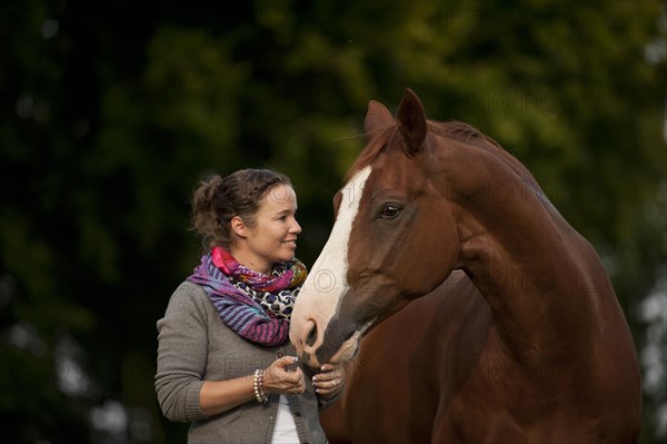 Woman standing next to a Hanoverian horse